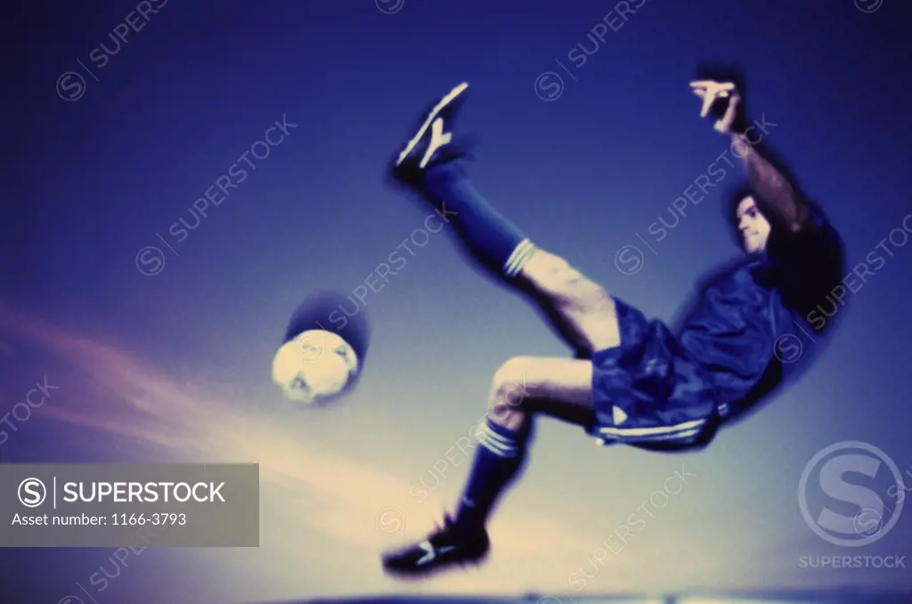 Soccer player jumping in mid air to kick a soccer ball