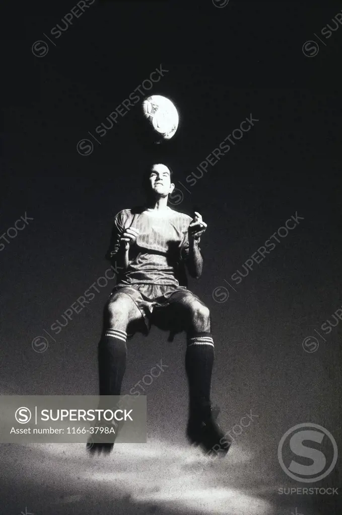 Low section view of a soccer player jumping in mid air to head a soccer ball