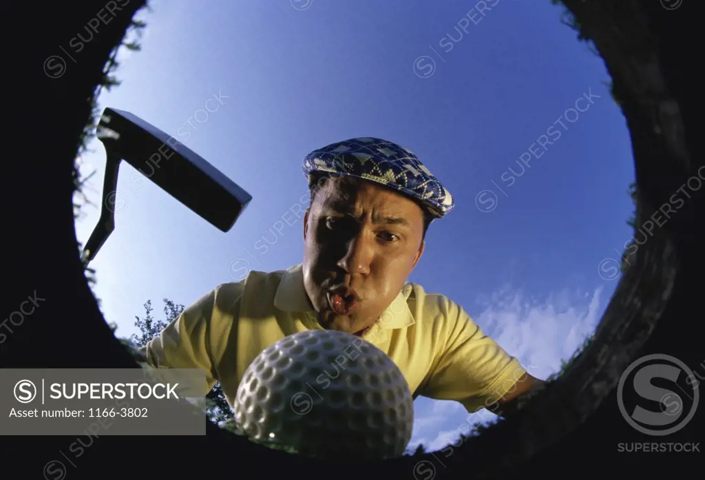 Low angle view of a golf ball falling into a cup
