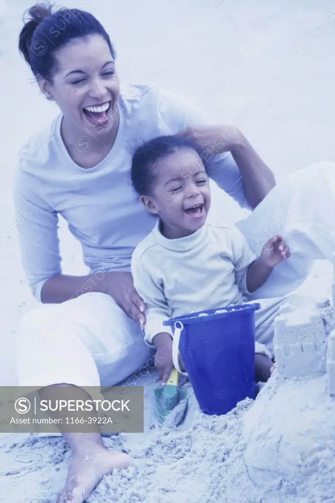 Young woman sitting on sand with her daughter