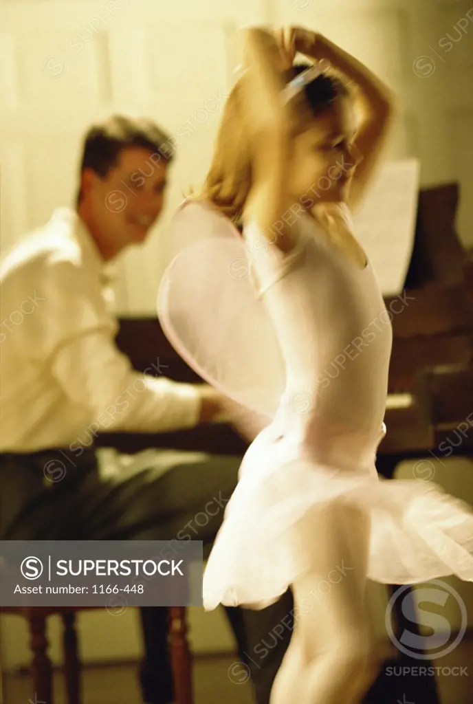 Father playing the piano with his daughter dancing