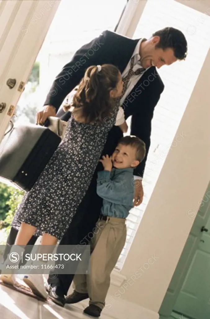 Boy and girl hugging their father in a doorway