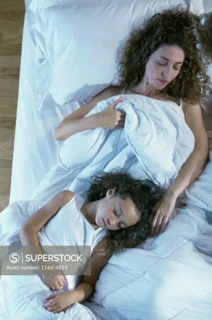 Mother sleeping with her daughter on a bed