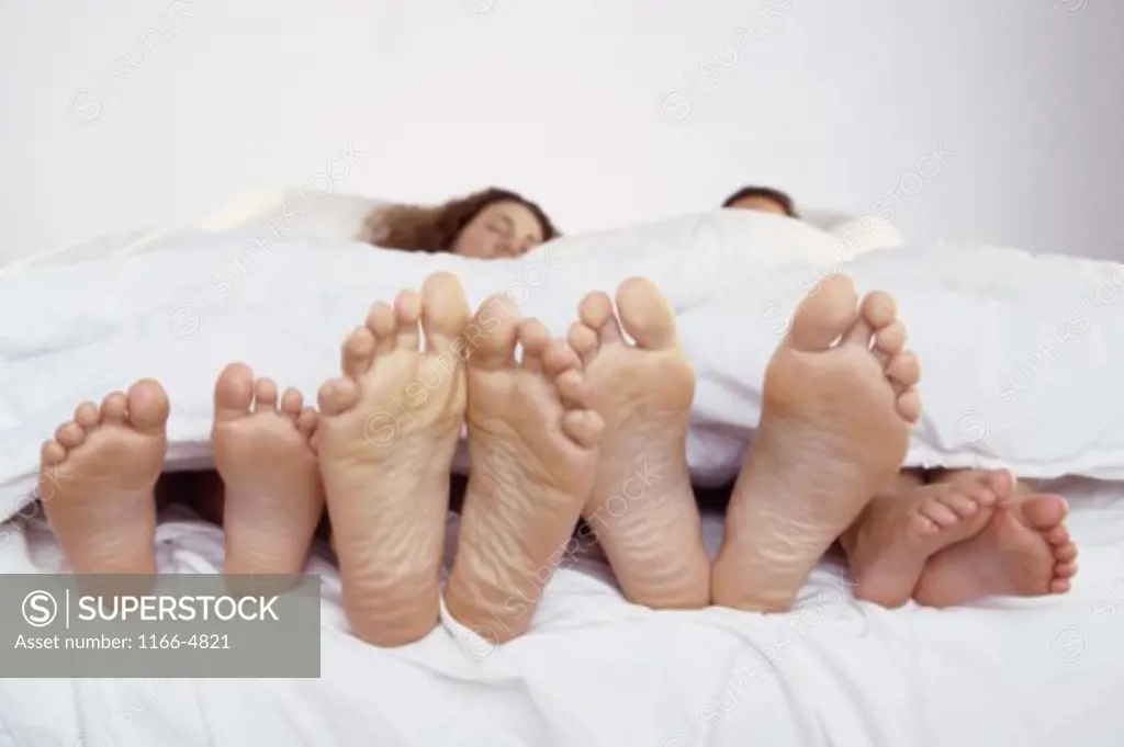 Mid adult couple sleeping with their son and daughter on a bed