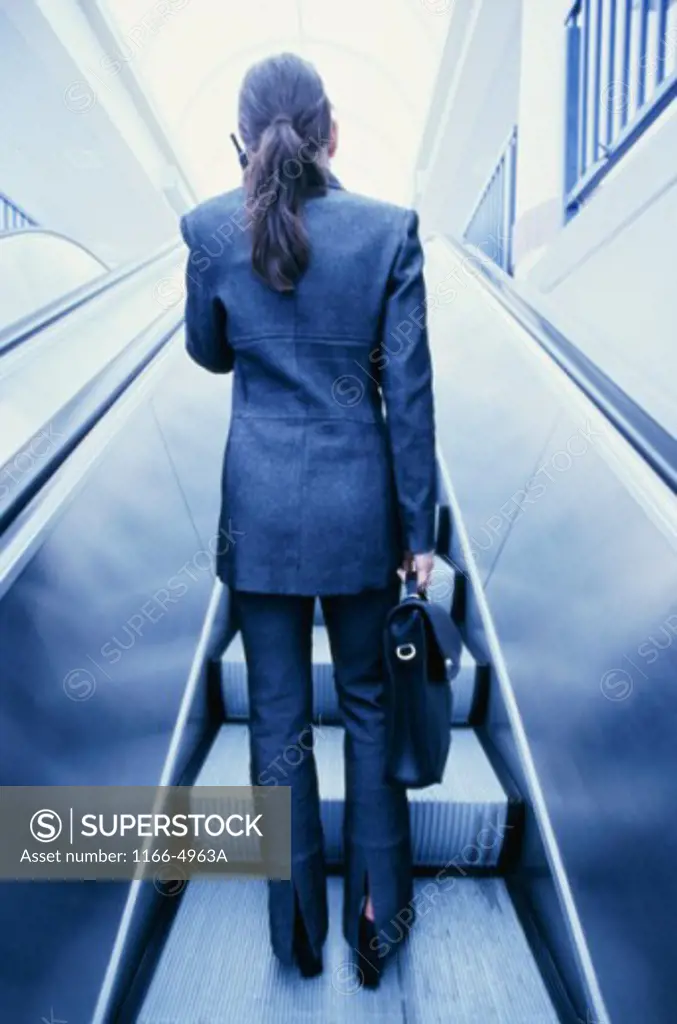 Rear view of a businesswoman standing on an escalator
