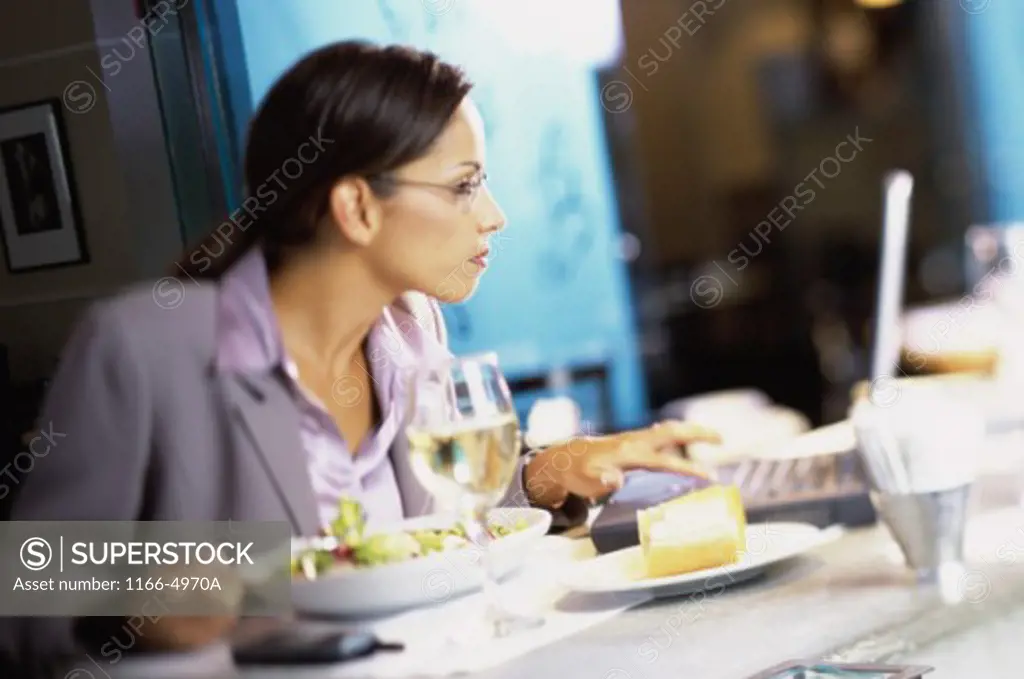 Side profile of a businesswoman sitting in a restaurant using a laptop