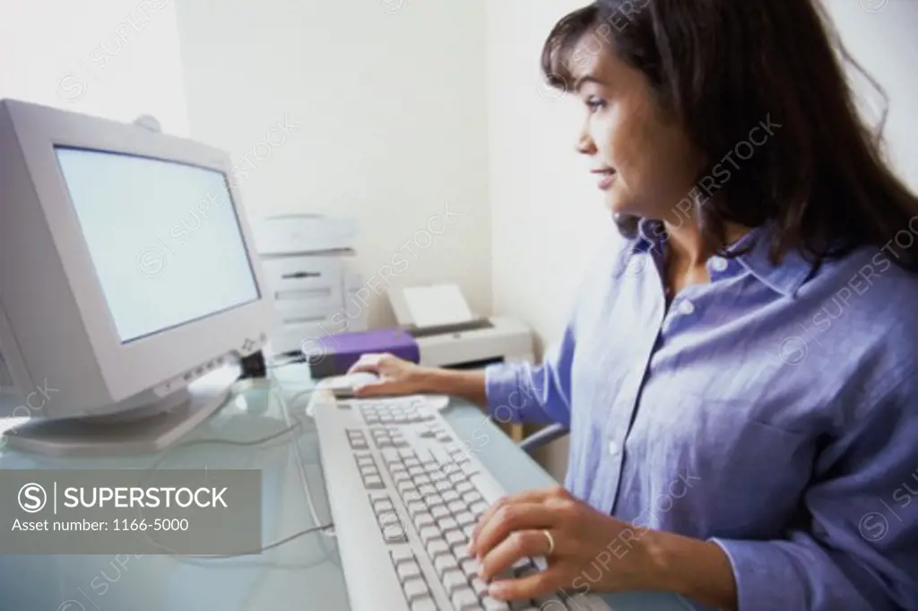 Side profile of a mid adult woman using a computer