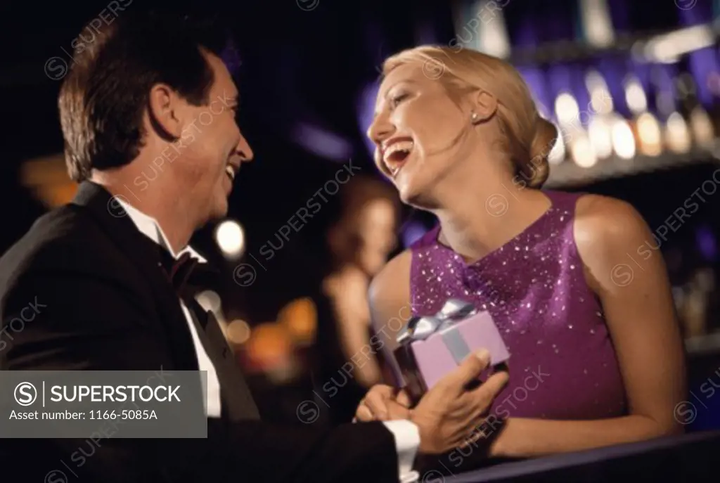Mid adult man handing a mid adult woman a gift