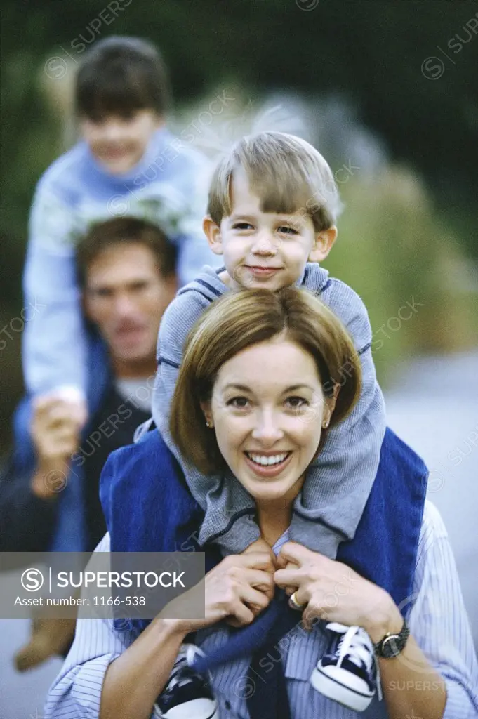 Portrait of parents carrying their son and daughter on their shoulders