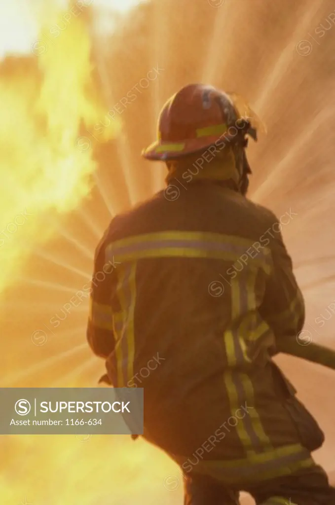 Rear view of a firefighter extinguishing a fire