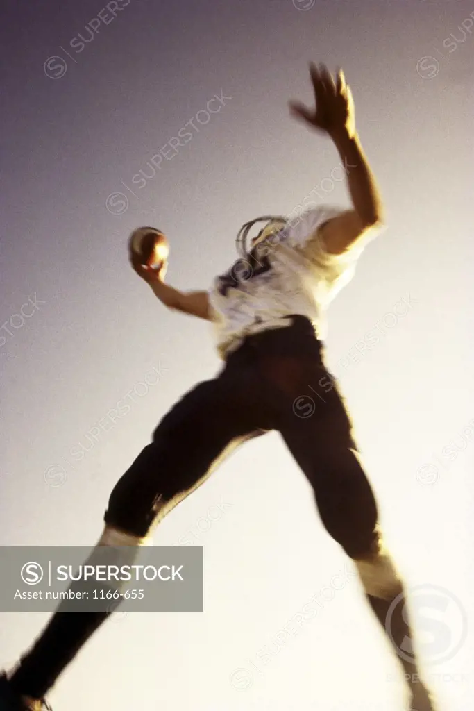 High angle view of a football player jumping in the air with a football