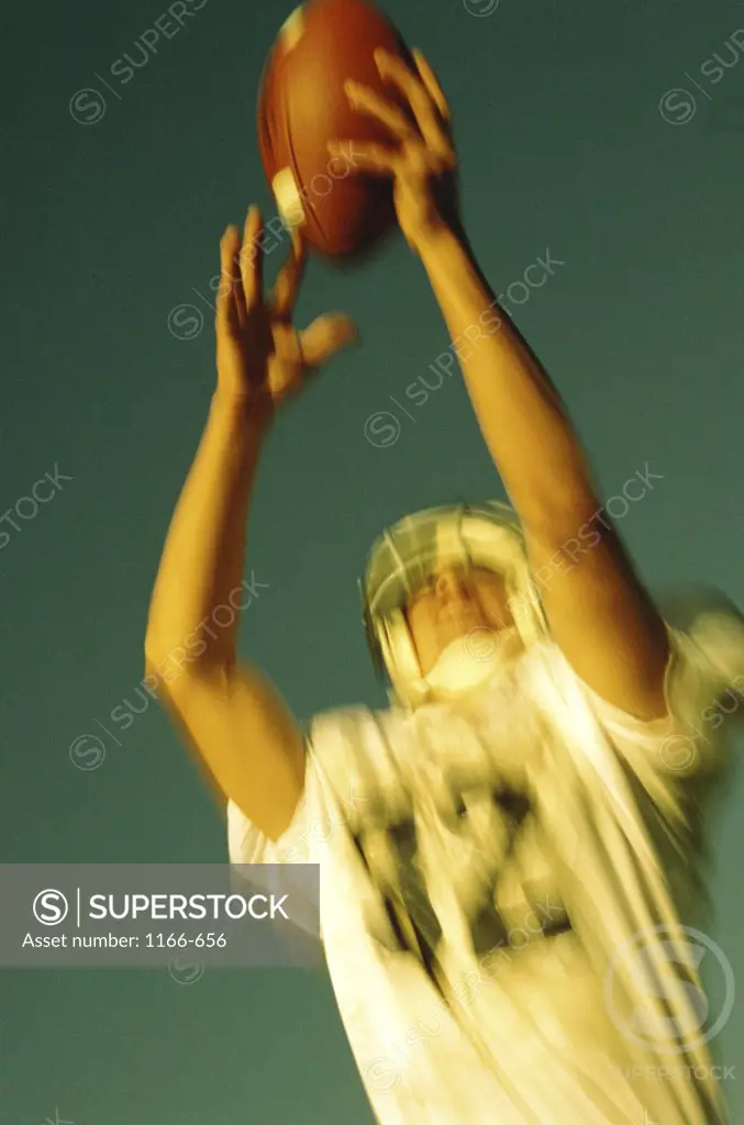 Football player reaching up to catch a ball