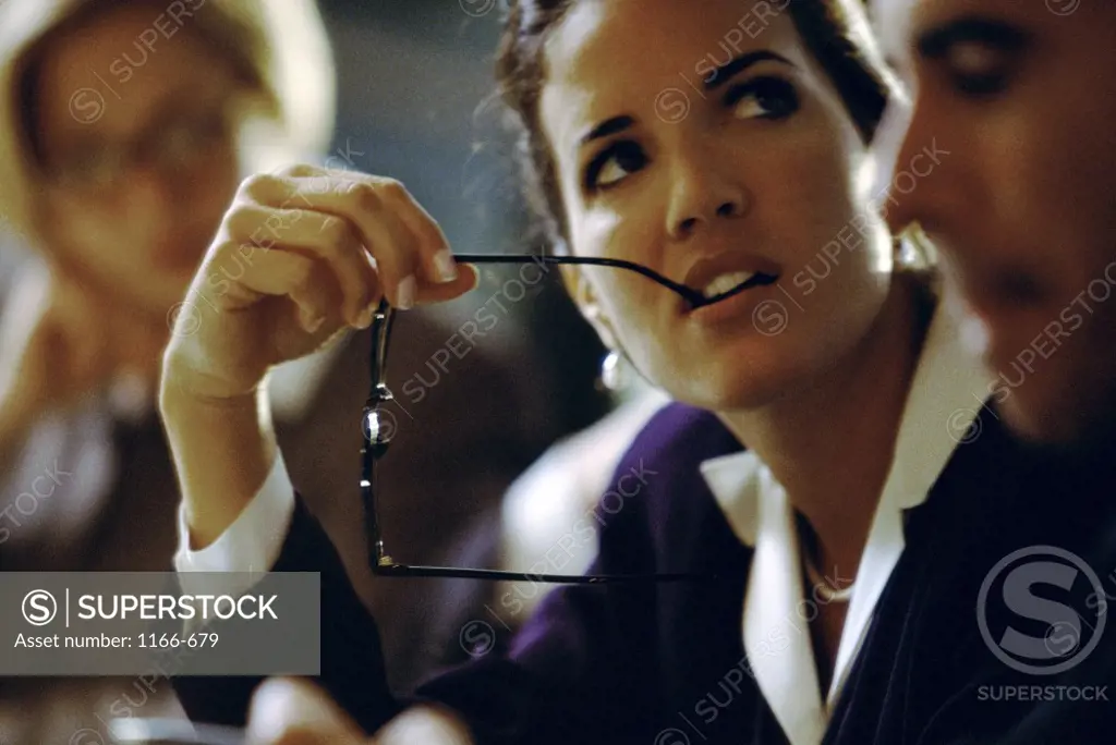 Businesswoman biting the tip of her eyeglasses