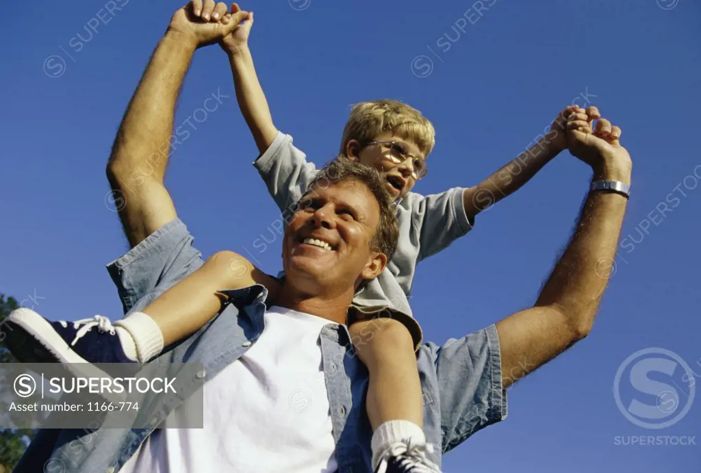 Low angle view of a man carrying his son on his shoulders
