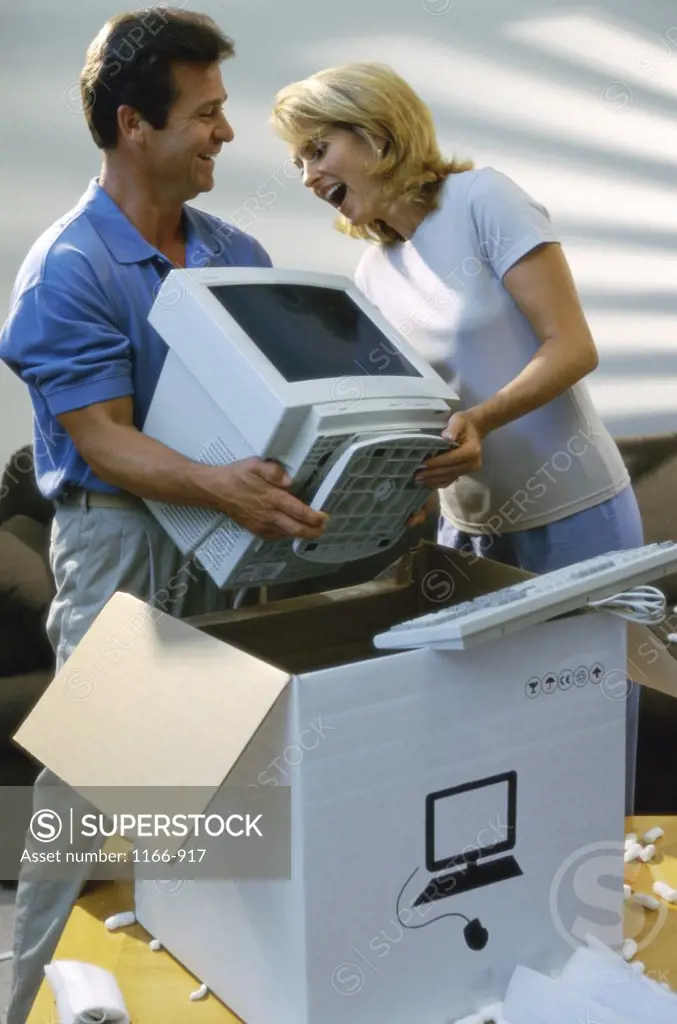 Young couple unpacking a computer monitor