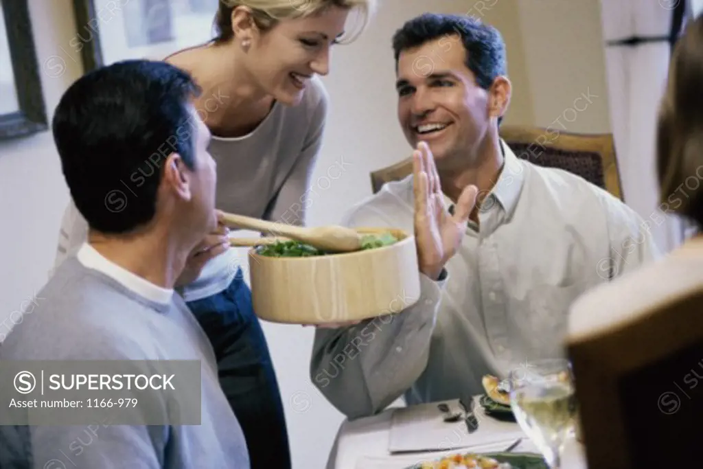 Mid adult woman serving food to two mid adult men