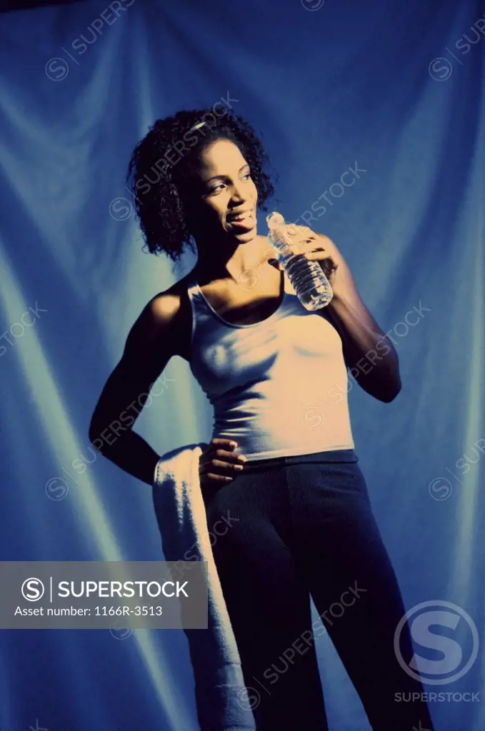 Young woman holding a bottle of water and a towel