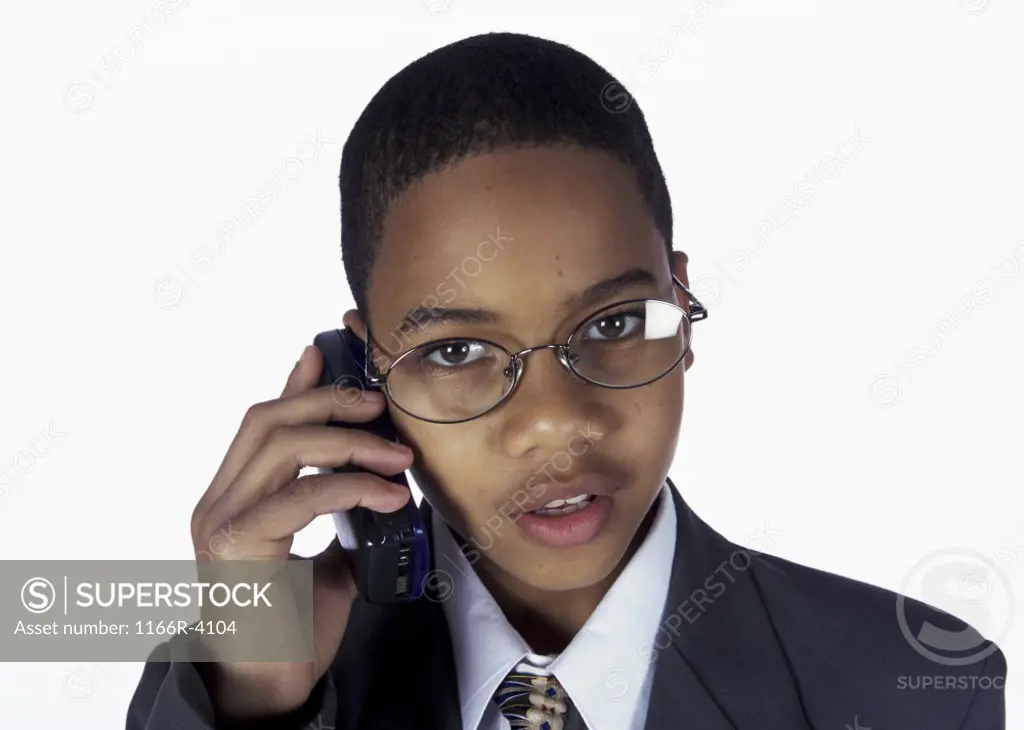 Portrait of a young boy dressed as a businessman talking on a mobile phone