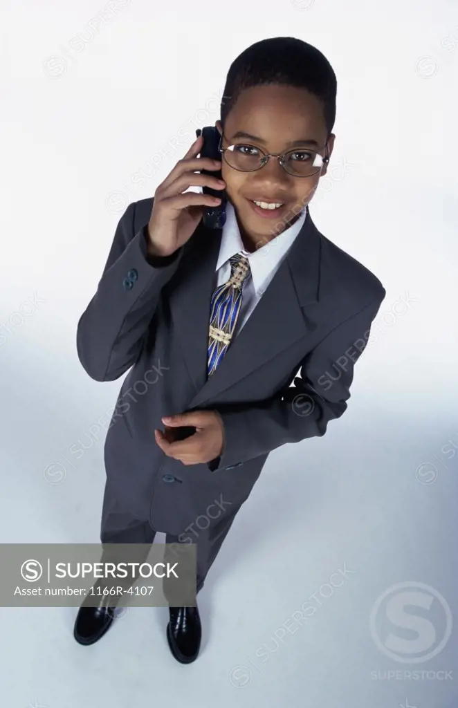 Portrait of a young boy dressed as a businessman talking on a mobile phone