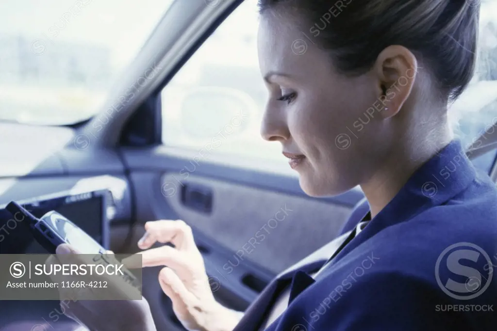 Side profile of a businesswoman operating a mobile phone in a car