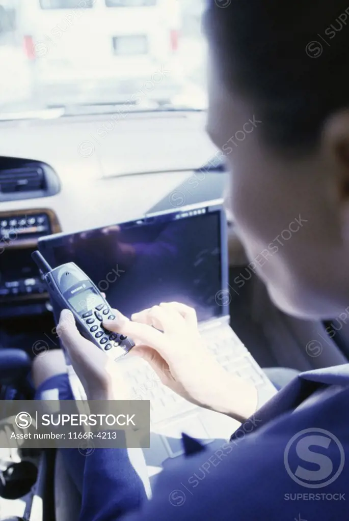 Rear view of a businesswoman operating a mobile phone in a car