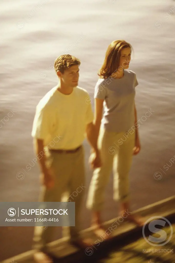 High angle view of a young couple standing at the edge of a lake
