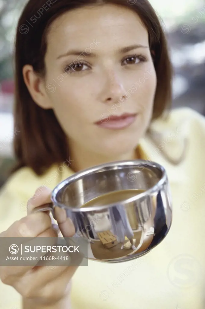 Portrait of a young woman holding out a teacup