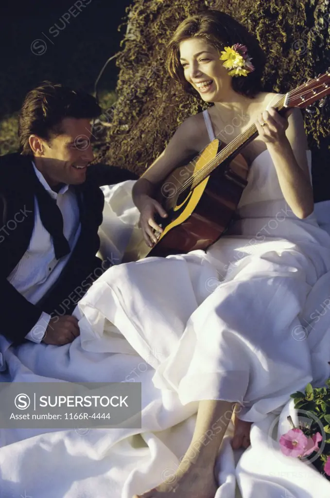 Bride and groom sitting together playing a guitar