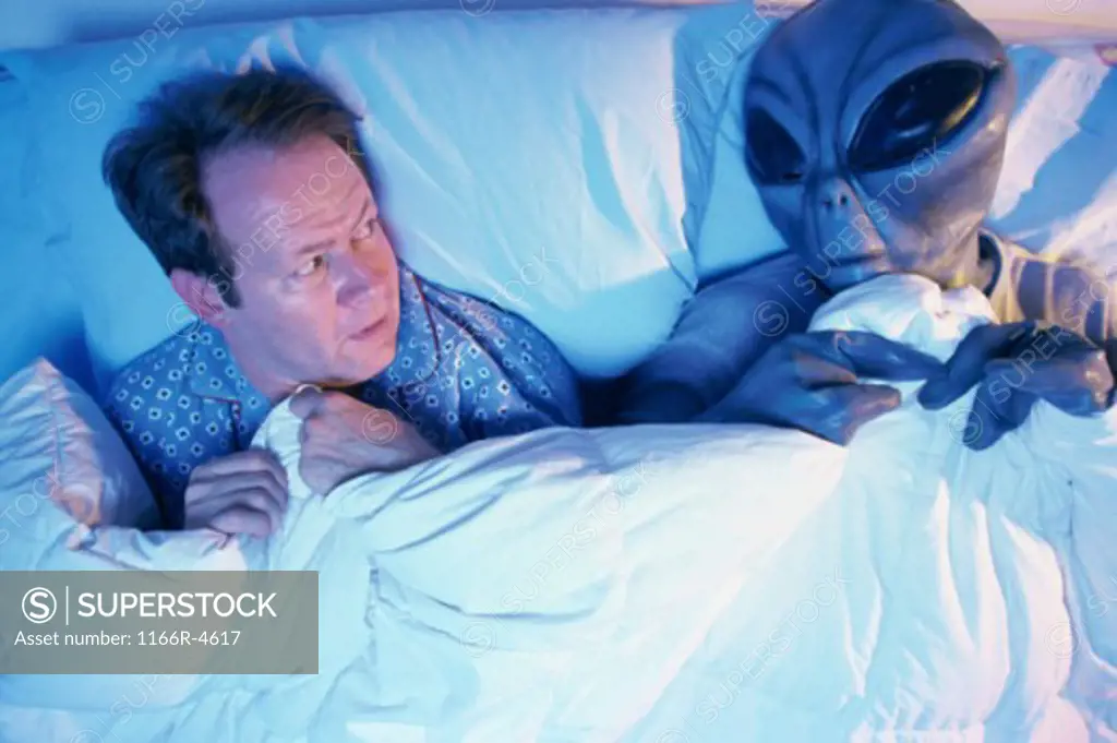 Man lying in bed with an alien