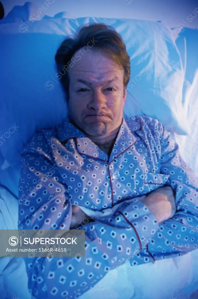 Portrait of a man lying in the bed pouting