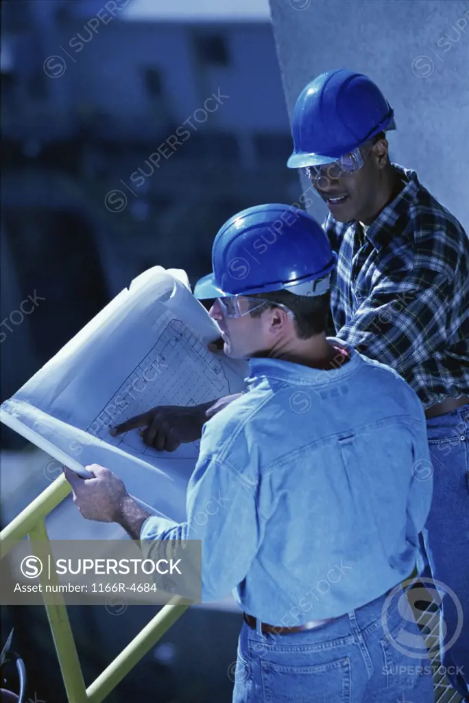 High angle view of two foremen working on blueprints