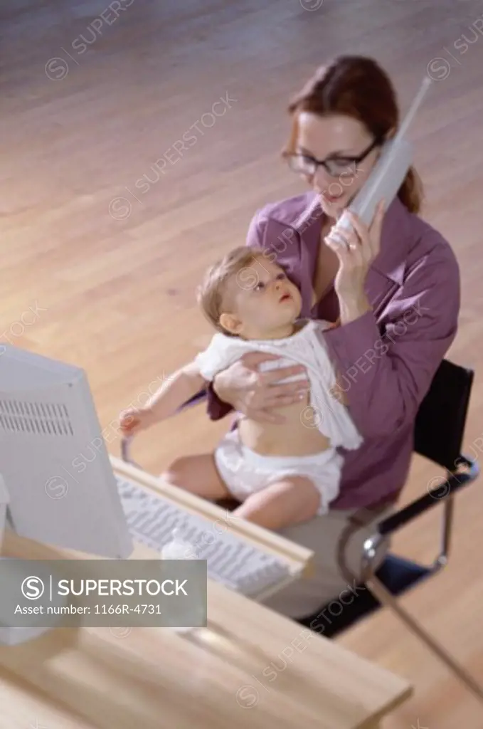 Mother talking on a telephone holding her baby girl