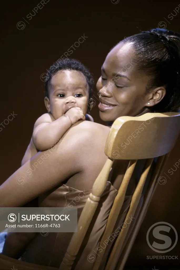 Side profile of a mother sitting on a chair holding her baby boy