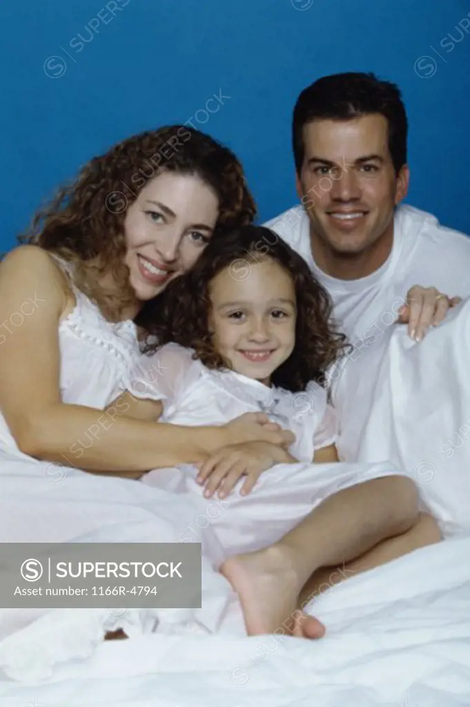 Portrait of parents with their daughter lying on a bed