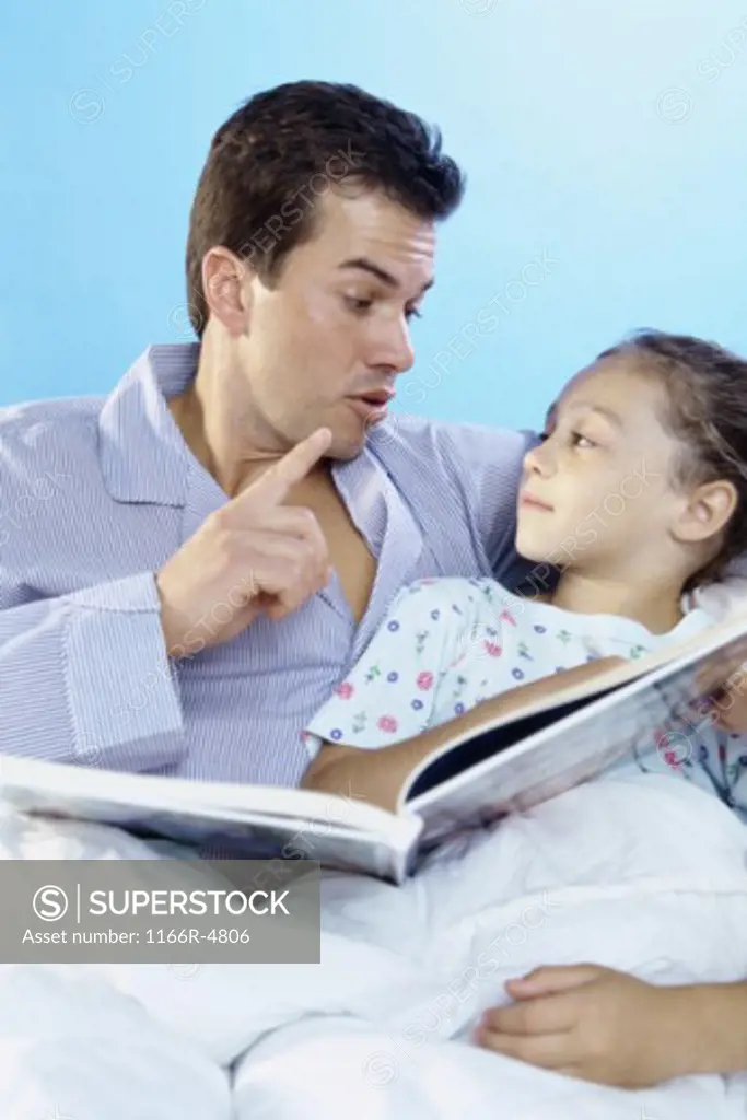 Father telling his daughter a bedtime story in bed