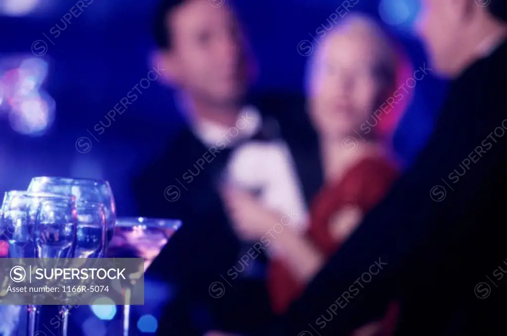 Glasses on a bar with people in the background