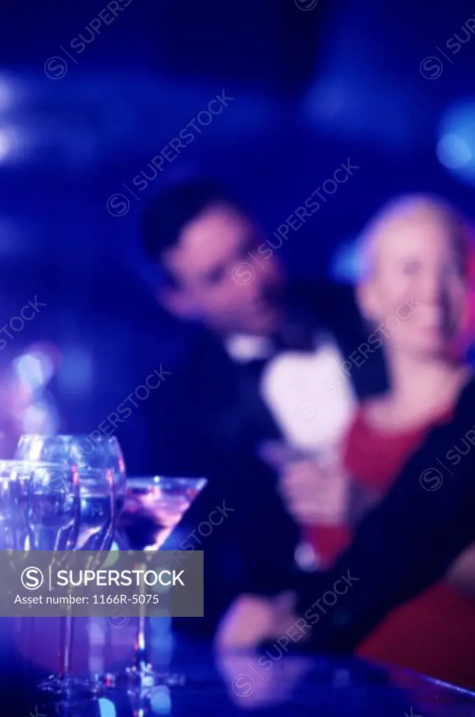 Glasses on a bar with a couple in the background