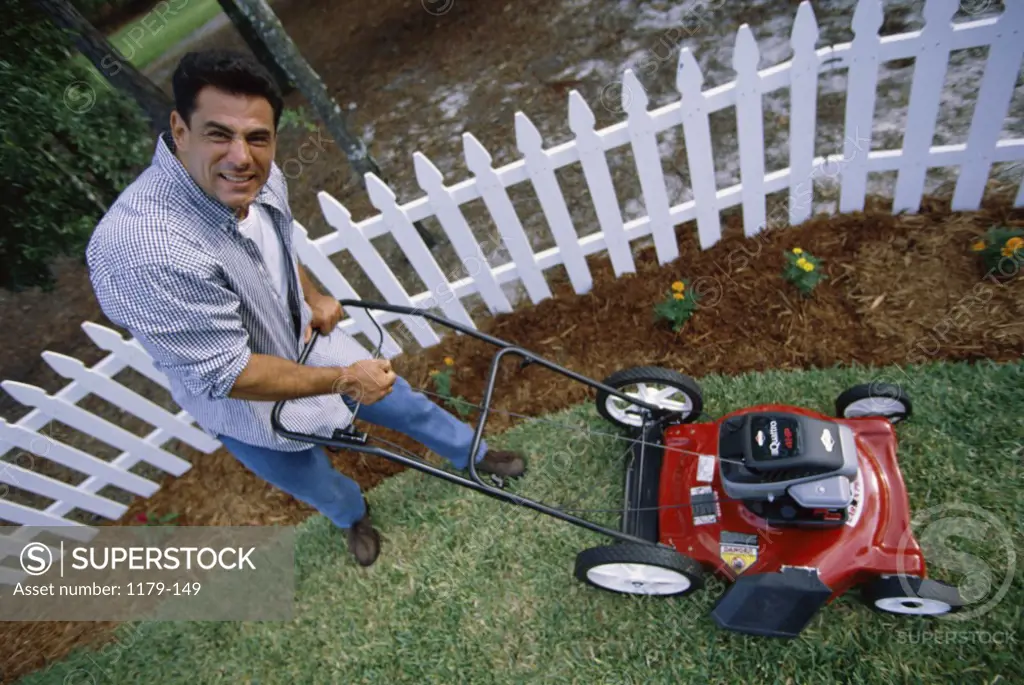 Portrait of a mid adult man pushing a lawn mower