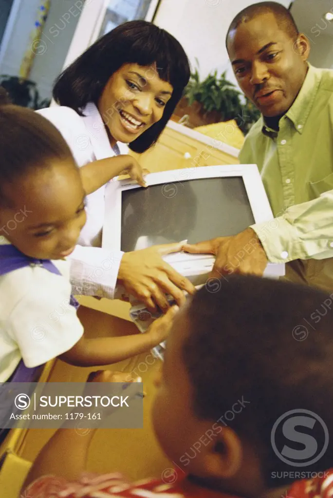 Son and daughter helping their parents unpack a computer monitor