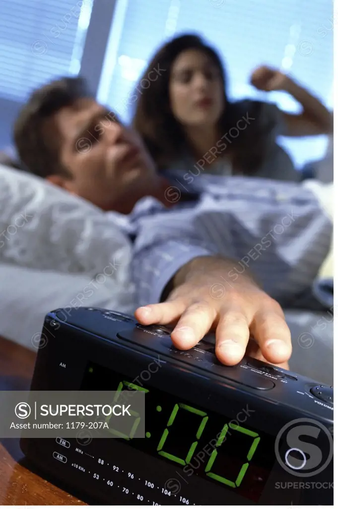 Young man reaching for an alarm clock
