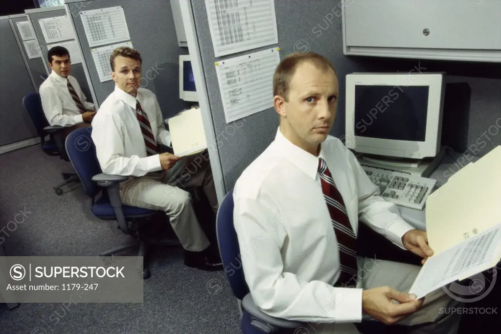 Portrait of three businessmen working in office cubicles