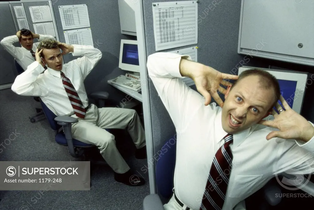 Three businessmen sitting in office cubicles