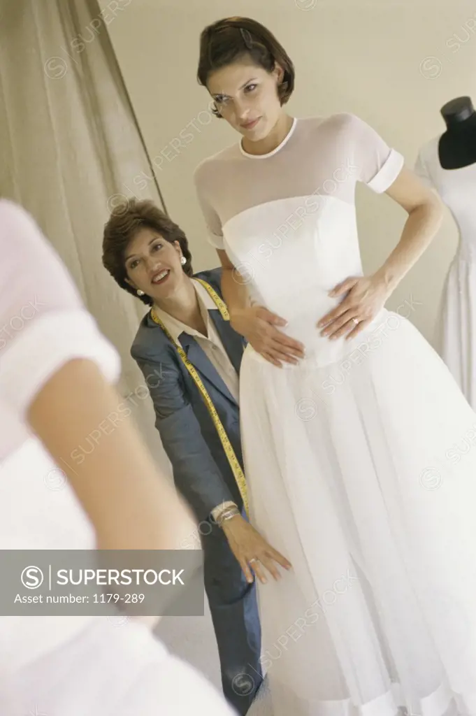 Mid adult woman adjusting a bridal gown on a young woman