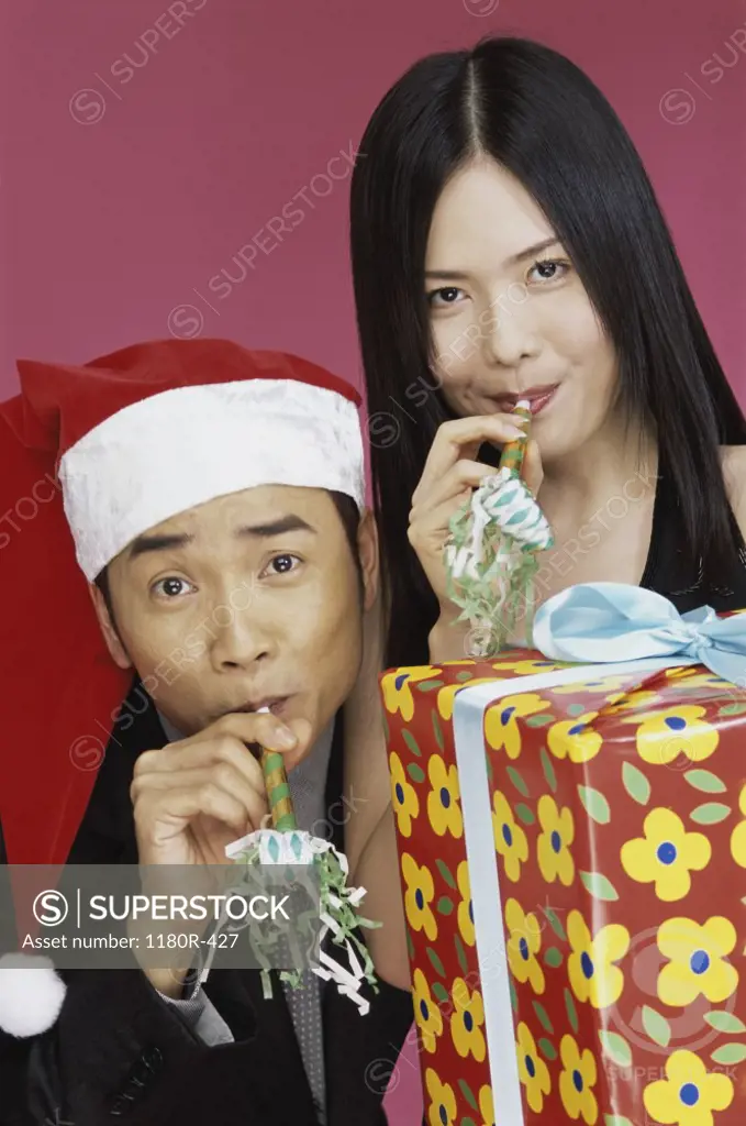 Portrait of a young couple with party hornblowers and a gift