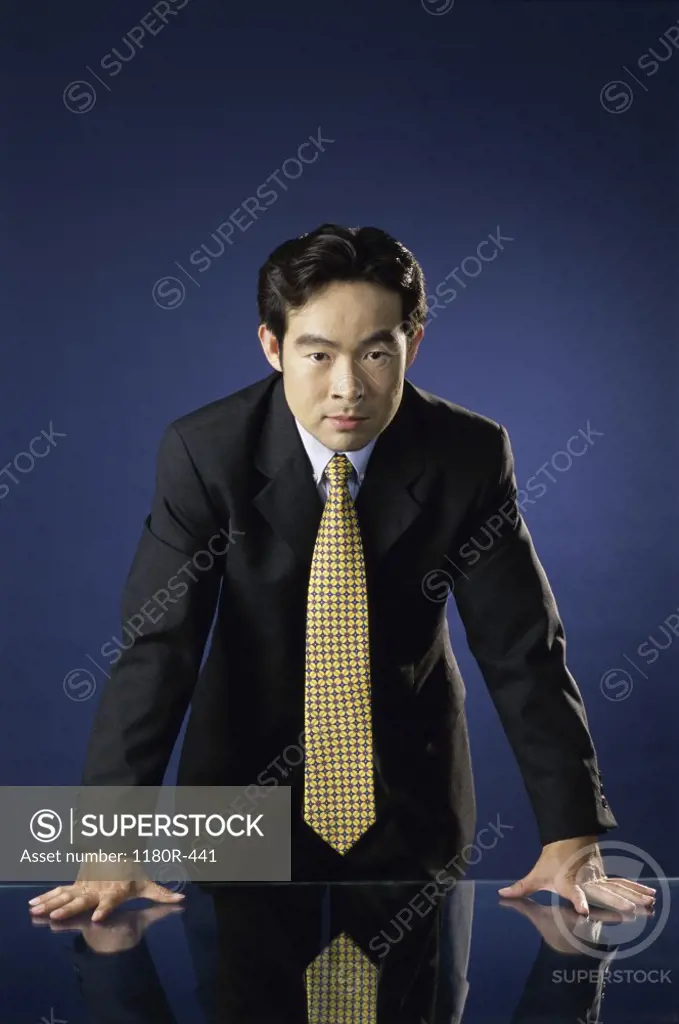 Portrait of a businessman leaning against a desk