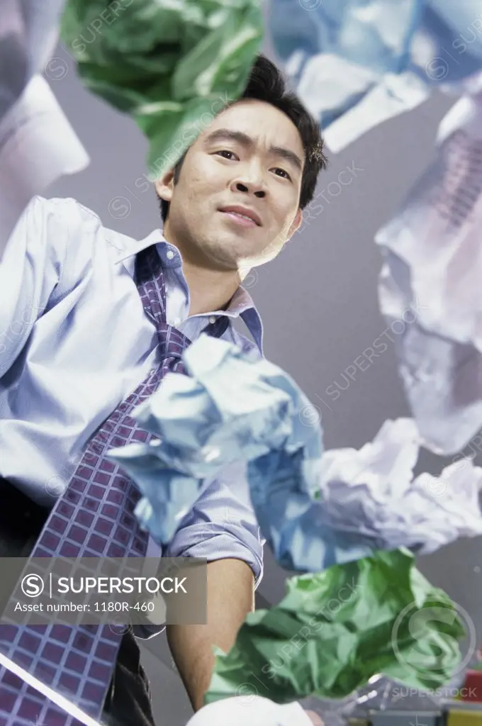 Low angle view of a businessman with crumpled paper around him
