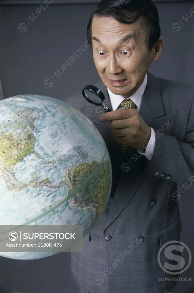 Businessman looking at globe with a magnifying lens