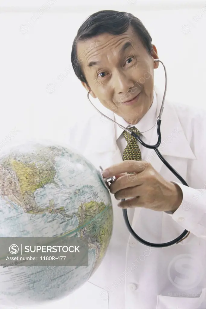 Portrait of a male doctor holding a stethoscope on a globe