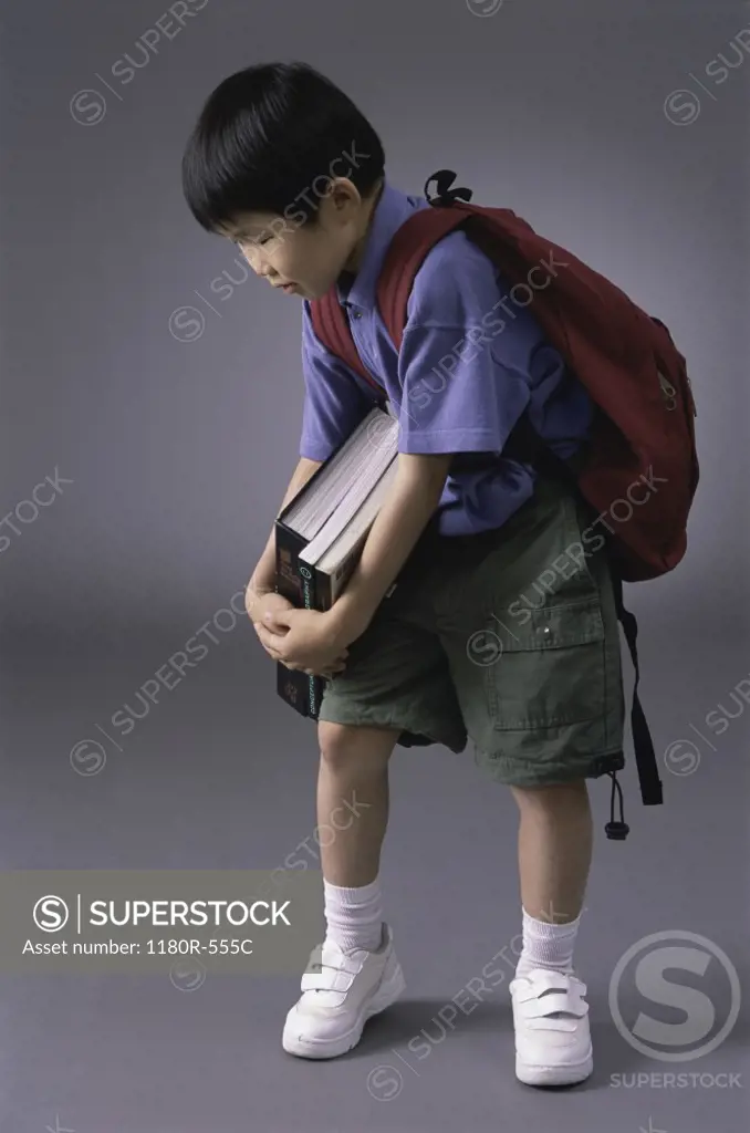 Boy carrying books and a backpack