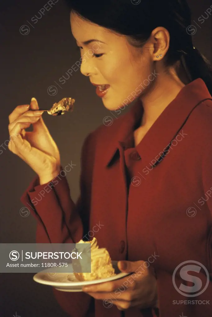 Side profile of a young woman eating a slice of cake